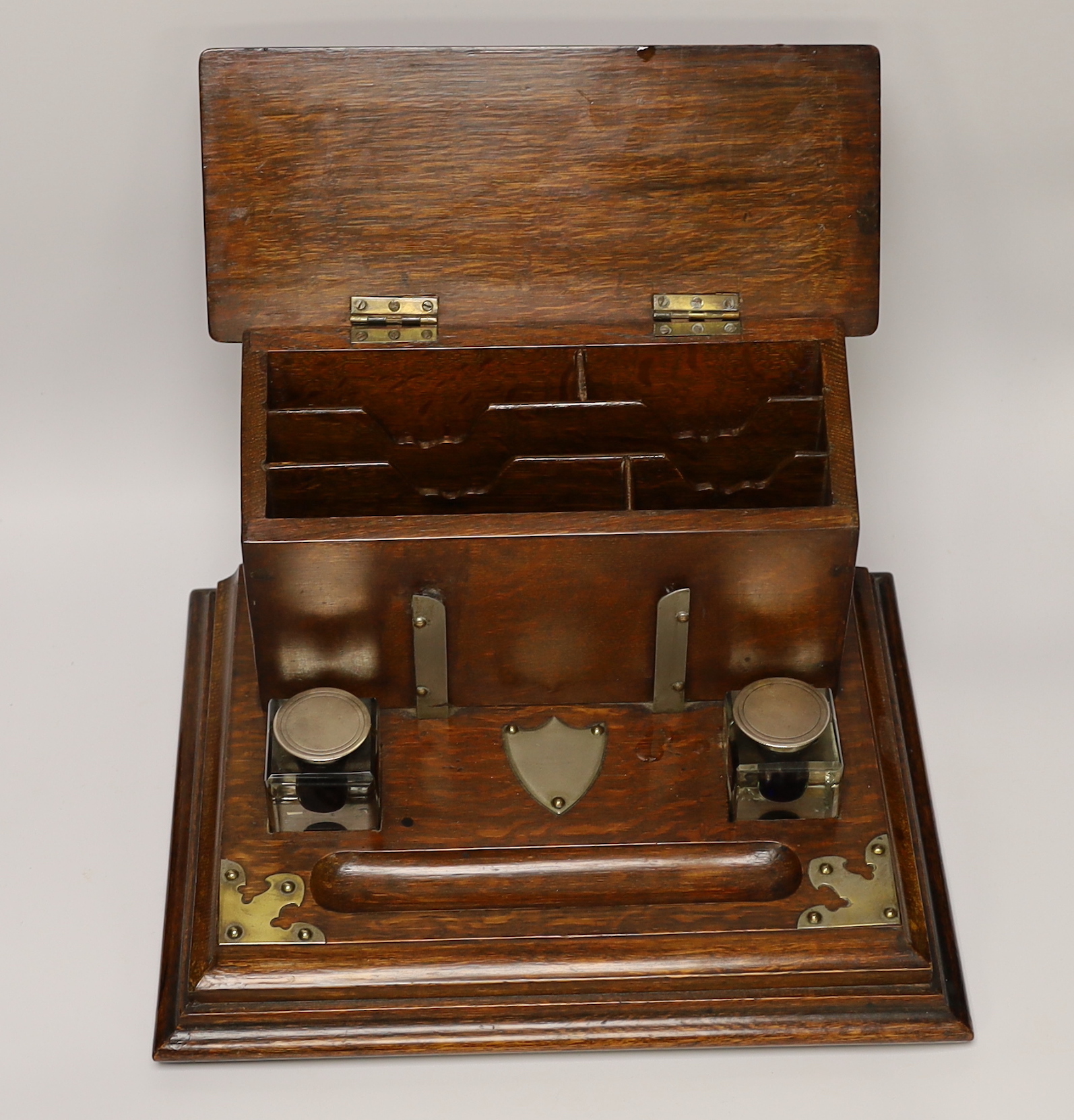 A Victorian brass mounted oak desk stand with two silver mounted glass inkwells, 35cm wide